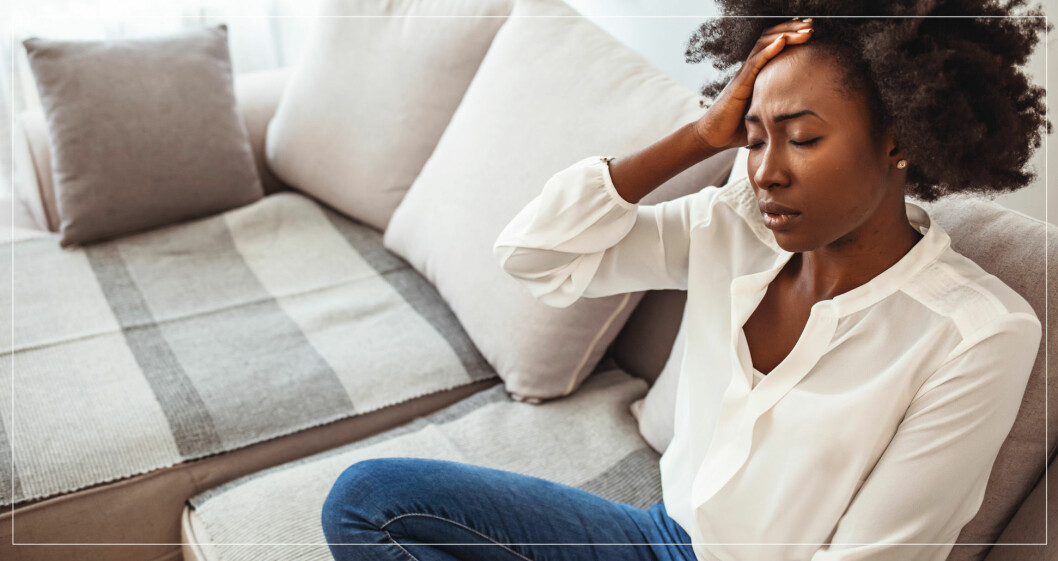Kvinna i soffa med huvudvärk på grund av östrogenbrist.