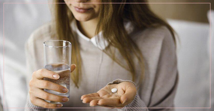 Kvinna håller i en tablett och ett glas vatten