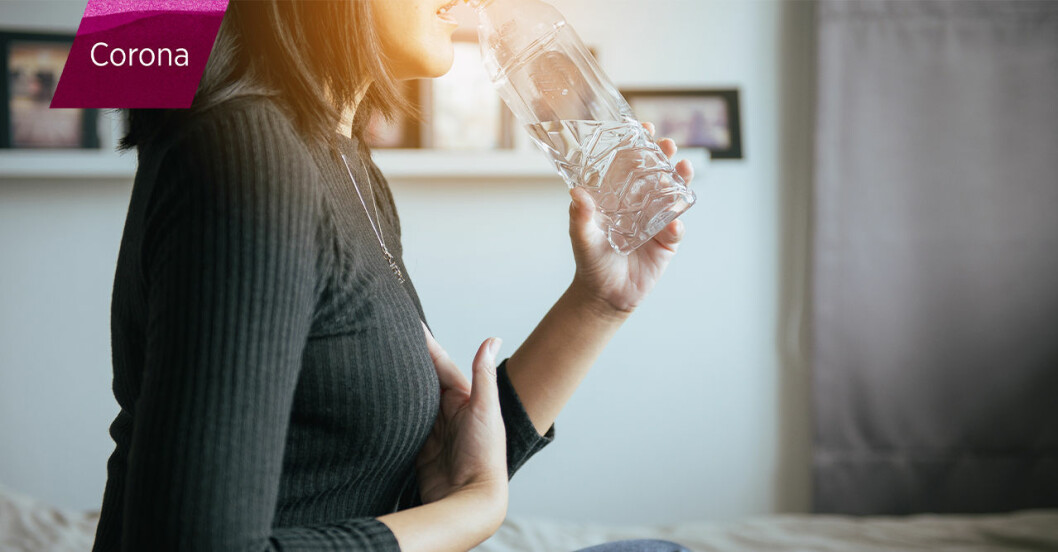 Kvinna med halsbränna sväljer ner ett piller med vatten