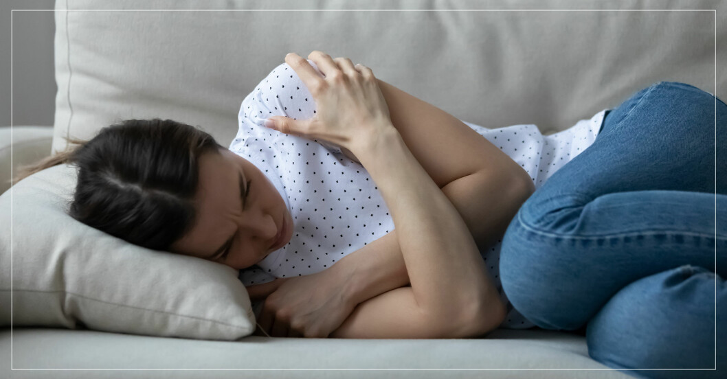 kvinna med magsmärtor ligger och är deprimerad i soffan