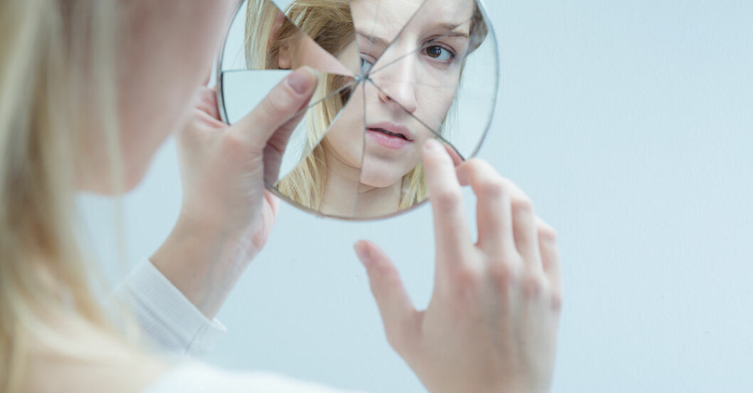 kvinna som tittar i en trasig spegel
