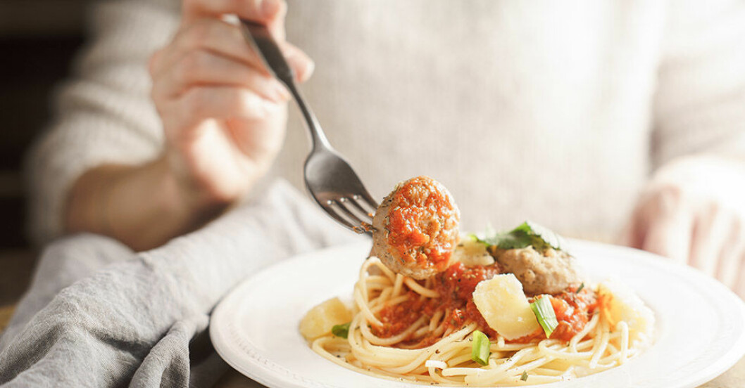 kvinna som äter portion med spagetti och köttbullar