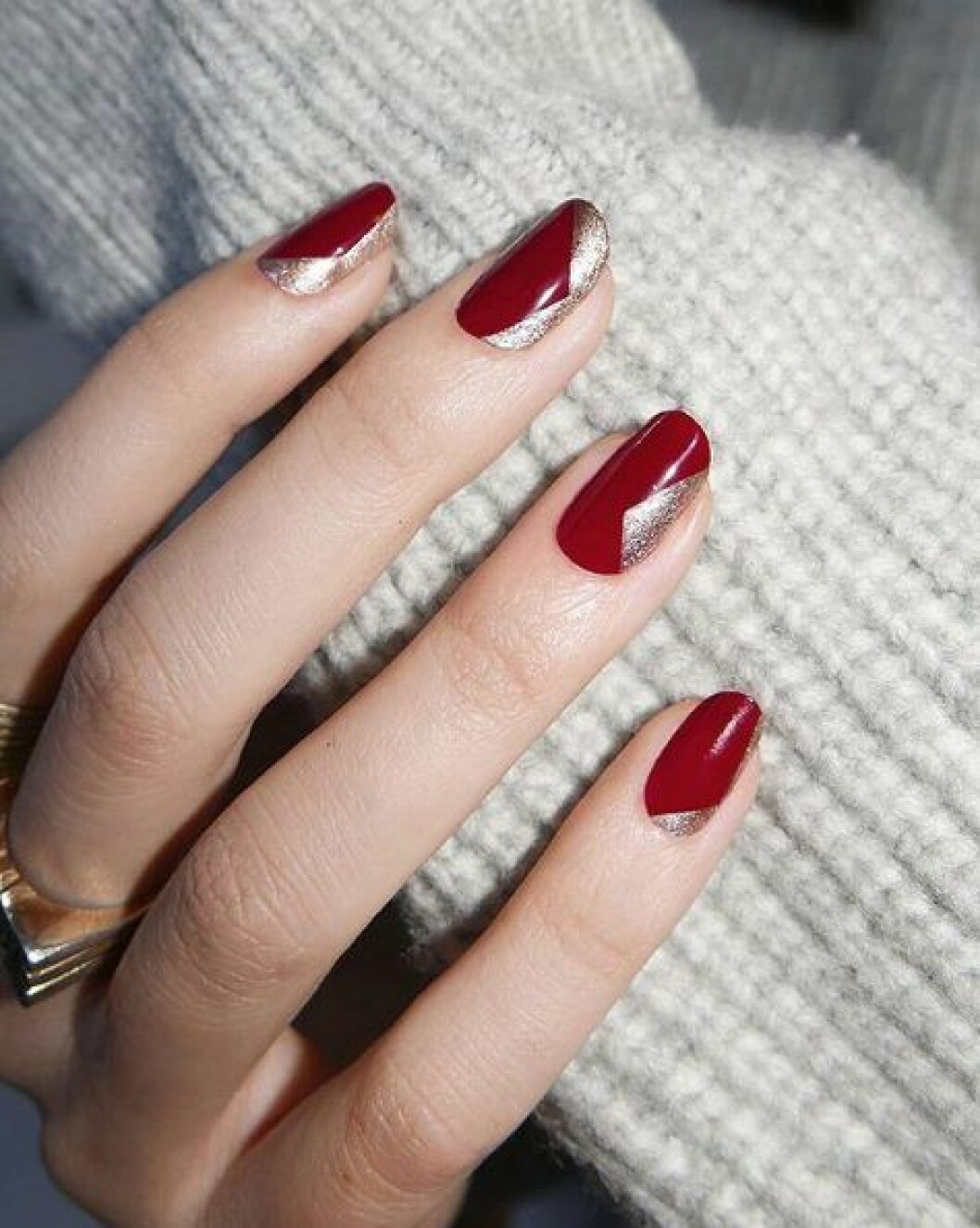 En bild på en nagellacksmanikyr i de juliga färgerna rött och guld. 
