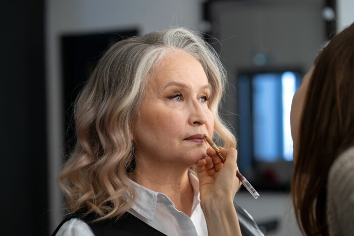 makeup-artist målar äldre kvinna med läppenna