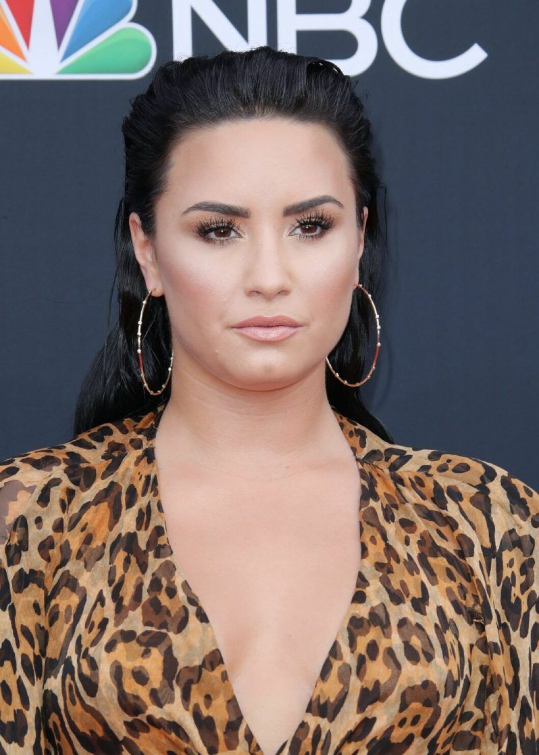 Demi Lovato med bakåtslickat hår och stora örhängen