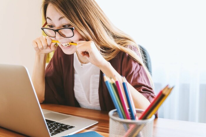 Kvinna biter på en penna stressad framför datorn
