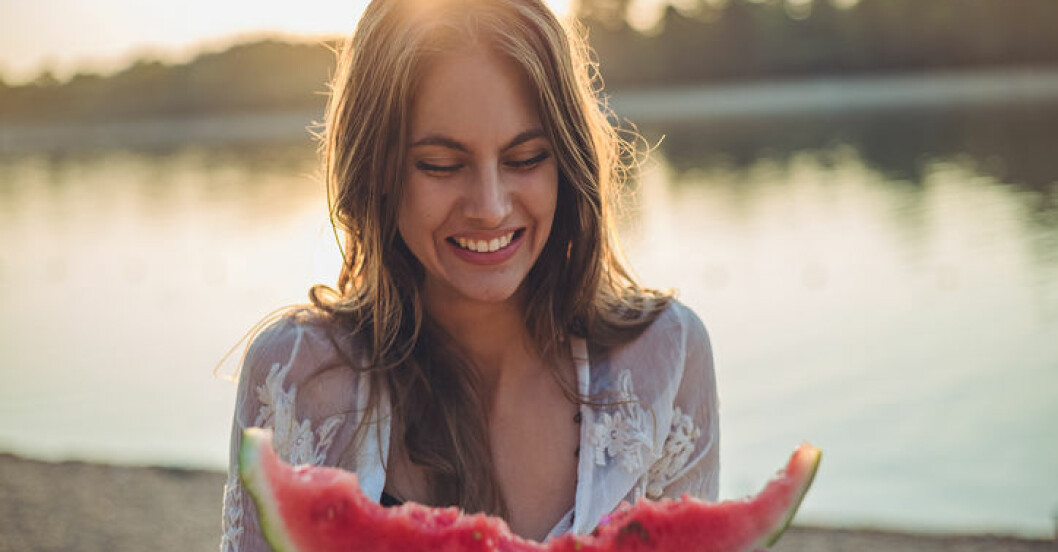 Kvinna håller i vattenmelon och ler