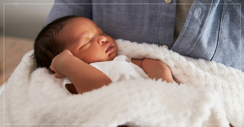 en bebis i vit body ligger i en vit filt och blundar