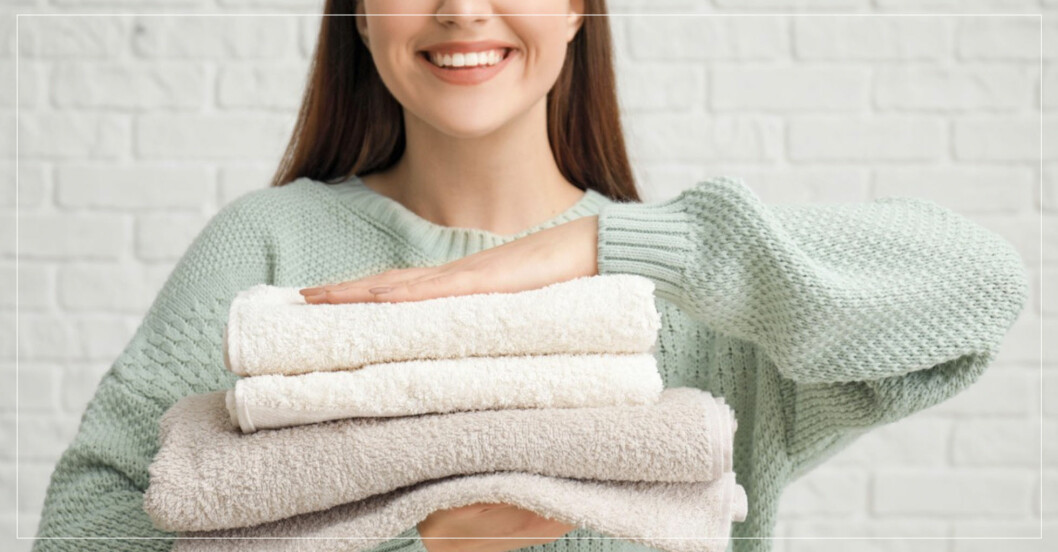 kvinna som håller en hög med nytvättade handdukar
